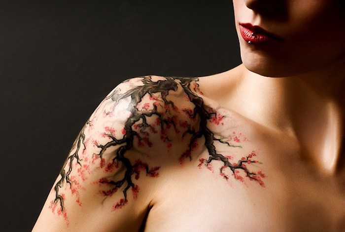 frau mit kirschblüten tattoo am schulter, zweig mi roten blüten