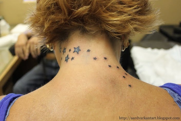 idee für einen stern tattoo für frau - ein schwarzer tattoo mit kleinen und großen schwarzen und blauen sternen auf dem rücken