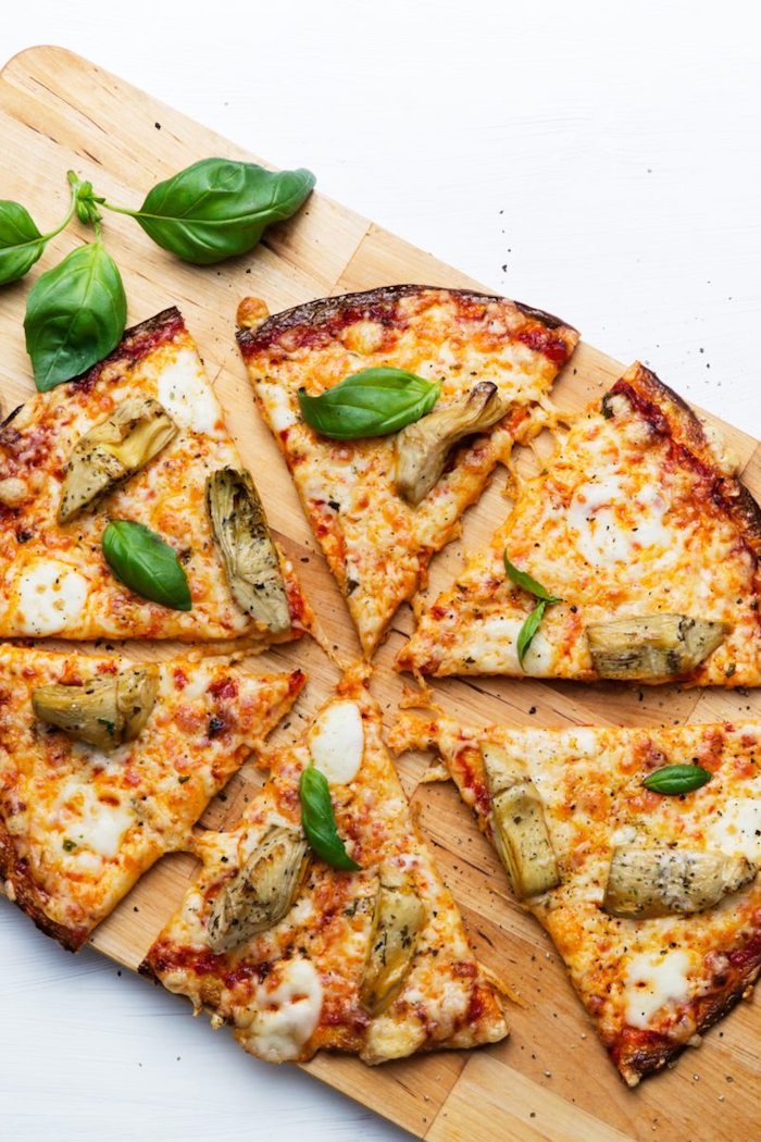 schnelle low carb rezepte pizza aus brokkoli oder blumenkohl gemischt mit eier als unterlage und garniert mit gemüse, bläter basilikum und mozzarella
