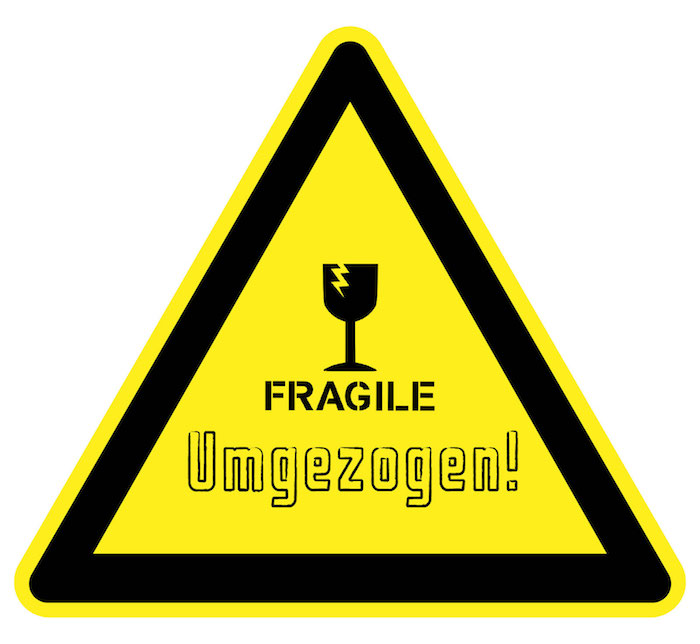 ein lustiger Schild mit der Anschrift: Fragile Umgezogen, gelber Triangel-Schild mit schwarzen Kanten und einem zerbrochenen schwarzen Weinglas
