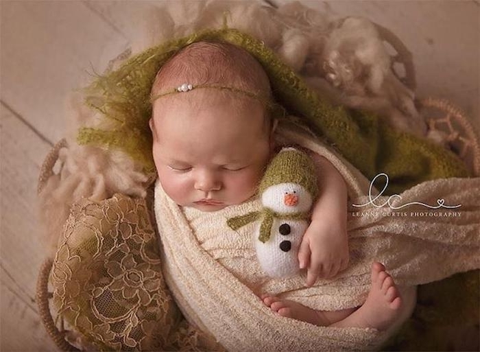 ein Neugeborenes mit dem Spielzeug von Schneemann - lustige Bilder zu Weihnachten