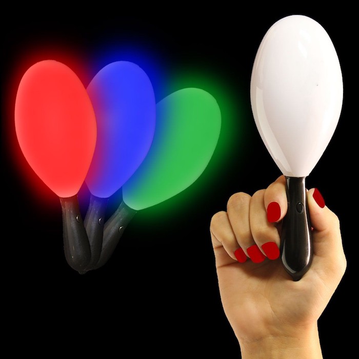 leuchtende Maracas mit LED-Lampen, Rasseln aus Plastik mit LED-Beleuchtung, Frauenhand mit rot lackierten Nägeln, schwarzer Hintergrund