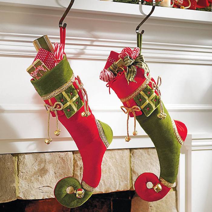 Nikolaus, eine rote und eine grüne Geschenksocke voll mit kleinen Geschenken, Socken, dekoriert mit kleinen Glöckchen und roten Perlen, offener Kamin im Wohnzimmer 