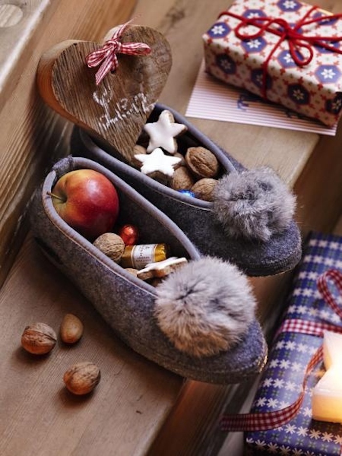 Pantoffel mit Troddel in grauer Farbe, Herzdeko aus Holz, kleines Geschenk in Papier mit Schneeflocken-Motiven, Kerze in der Form eines Sternes, Holztreppen, Weihnachtskarte, drei Walnüsse