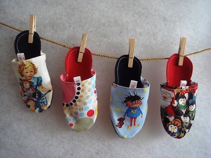vier Pantoffel mit Weihnatchsprint, die auf einem Seil mit Holzklammern zum Nikolaustag gehängt sind