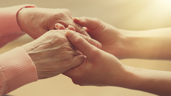 mit Liebe und Sorge um die Pflegebedürftigen, zwei Frauen halten Hände