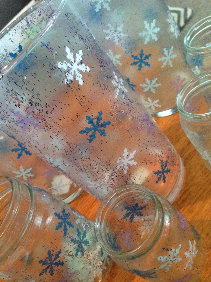 kleine Schneeflocken in blauer und weißer Farbe auf Weckgläser und Gläser beklebt