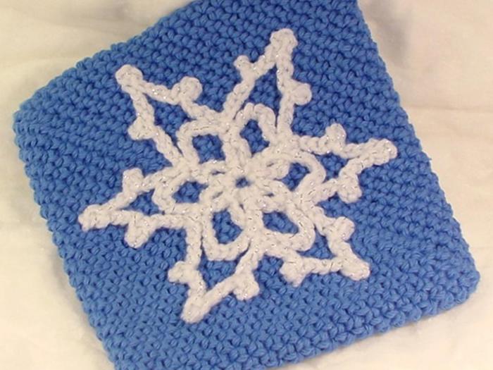 eine blaue gehäkelte Tüte mit einem weißen Schneeflocke als Dekoration - Schneeflocken Bilder