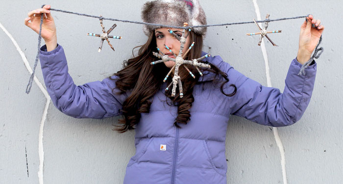 eine junge Dame hat Schneeflocken aus Stöckchen gebastelt - Fensterdeko basteln