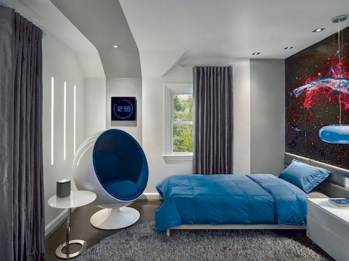 ein runder grauer Teppich, blaue Bettwäsche, weißer Tisch und ein moderner Sessel - Jugendzimmer gestalten