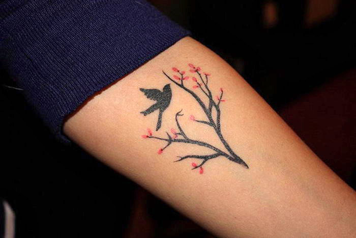 symbol für stärke und freiheit, kleine tärowierung mit vogel-motiv, zweig mit blüten