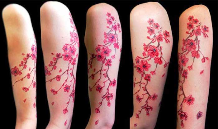 symbol für stärke, farbge tätowierung am oberarm, tattoo mit kirschblüten-motiv