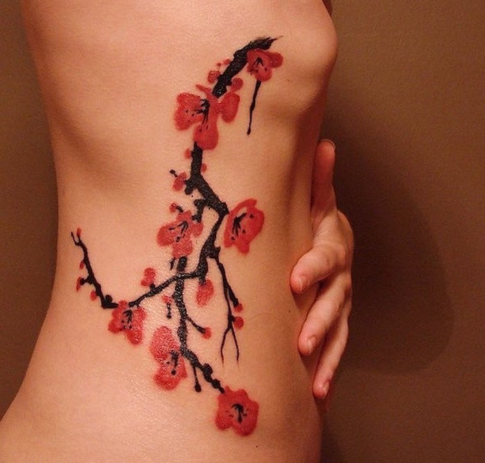 symbol für stärke, zweig mit roten kirschblüten an der körperseite, tattoos für frauen