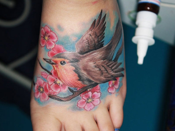 tattoo kirschblüten, bauner vogel auf zweig, farbige tätowierung am fuß