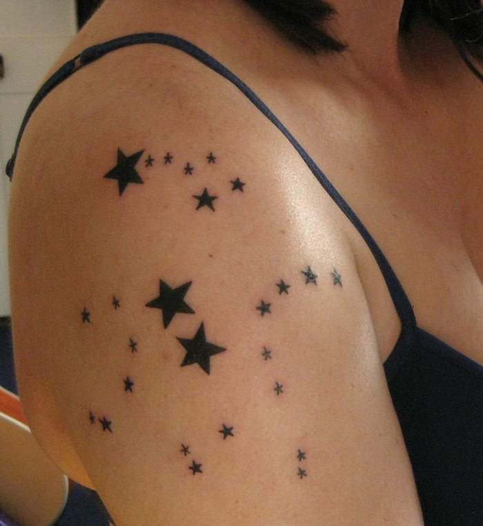 tattoo sterne arm - eine frau mit einem schwarzen tattoo mit vielen kleinen und großen schwarzen sternen