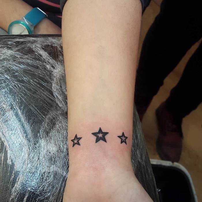 eine hand mit einem schwarzen tattoo sterne mit drei kleinen schwarzen sternen tattoo sterne handgelenk