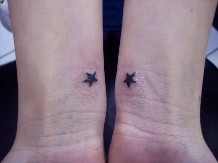 zwei hände mit tätowierungen mit zwei kleinen schwarzen sternen - tatoo sterne handgelenk
