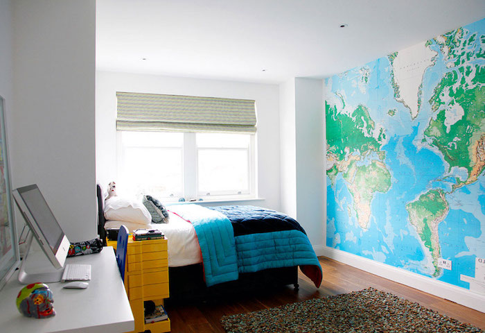 eine Fototapete mit der geografischen Weltkarte, blaue Bettdecke und weißer Schreibtisch - schöne Zimmer