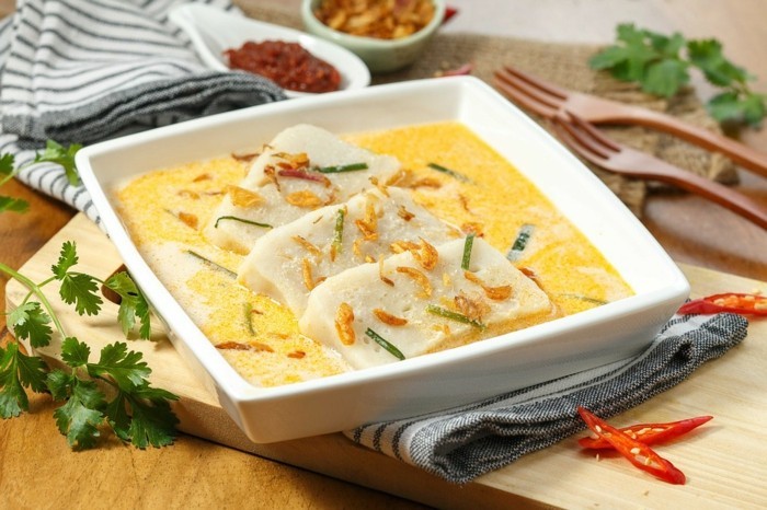 suppe mit tofu stücken servieren milchsuppe kräuter petersilie quadratische schüssel holzgabel paprika chilli