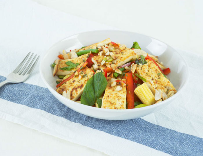 tofu rezept für einen schmackhaften salat mais blattsalat erdnüsse gabel auf dem tisch tischdecke weiß blau