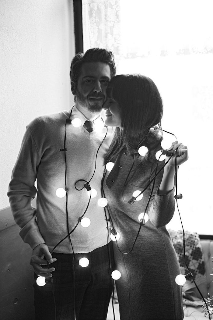 Weihnachtsfotos - zwei Verliebte fotografieren sich im Wohnzimmer mit Lichterkette