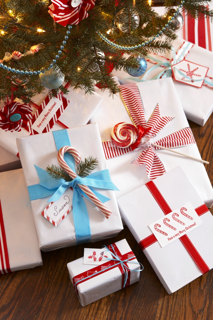 Viele Geschenke unter dem Weihnachtsbaum, verziert mit Tannenzweigen, Lutschern und Zuckerstangen