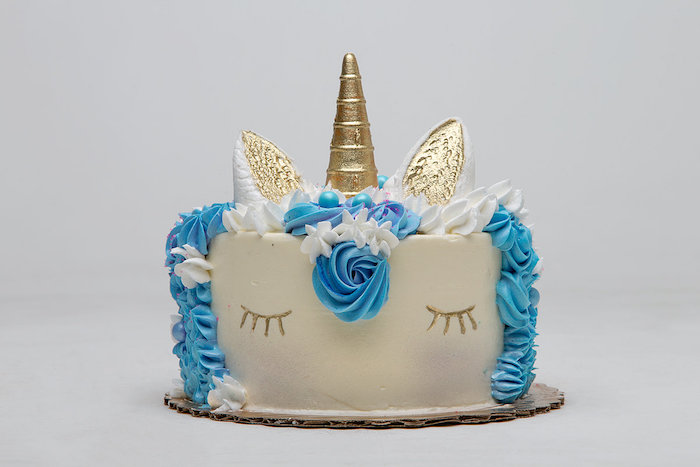 eine idee füreinhorn kuchen - hier ist eine weiße einhorn torte mit einer blauen mähne und mit einer blauen rose und mit einem goldenen langen horn - idee für einhorn kuchen deko 