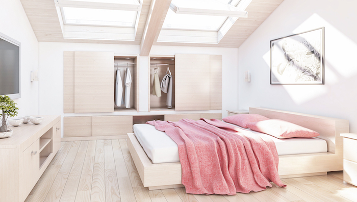 wohnung einrichten großes und helles schlafzimmer mit fesntern am dach dachfenster natürliches licht zulassen rosa bettdecke fernseher wandbild deko