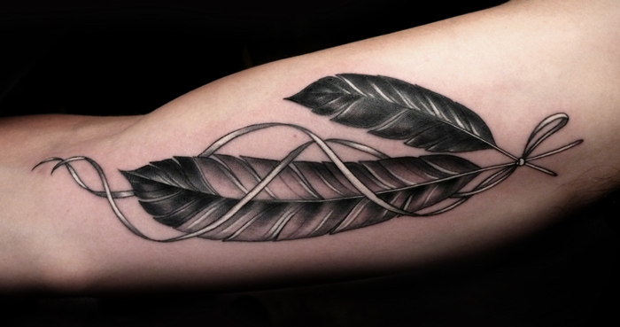 feder tattoo in schwarz und grau, oberarm tattoo mit indianischem motiv