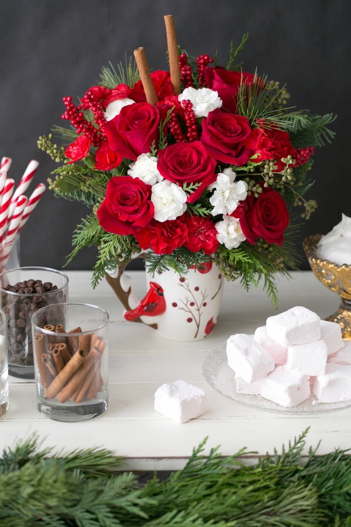 Weihnachtsgestecke - rote Rose und weiße Blumen in Kaffeebecher mit kleinen roten Vogel