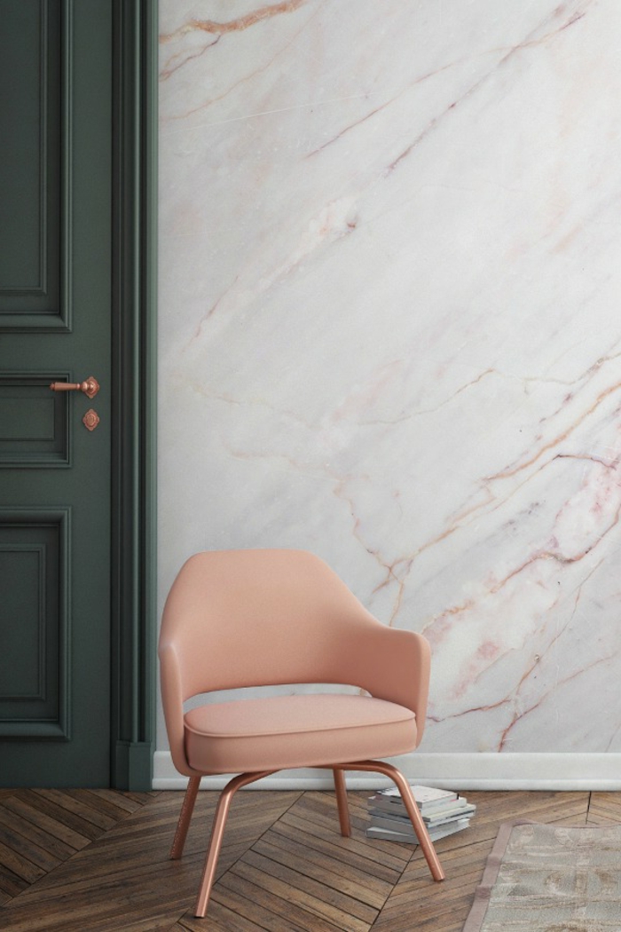 Lederstuhl in Apricot, Wandgestaltung in Marmor-Optik, dunkelgrüne Tür, Bücher auf dem Boden