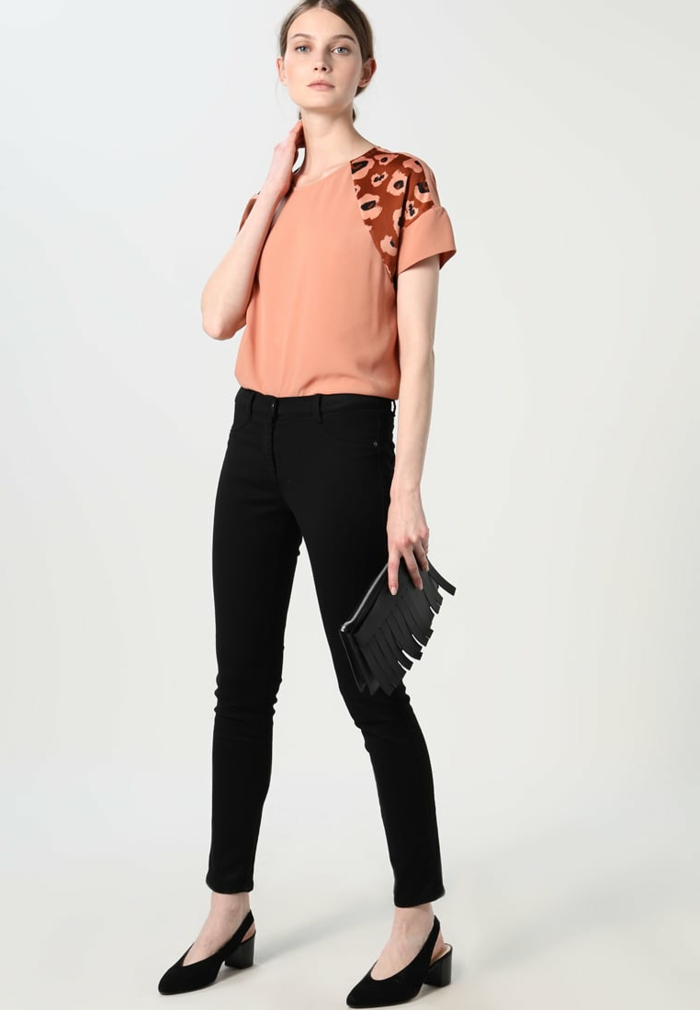 Elegantes Damenoutfit, Top in Apricot und schwarze Hose, Frau mit leichtem Tages-Make-up