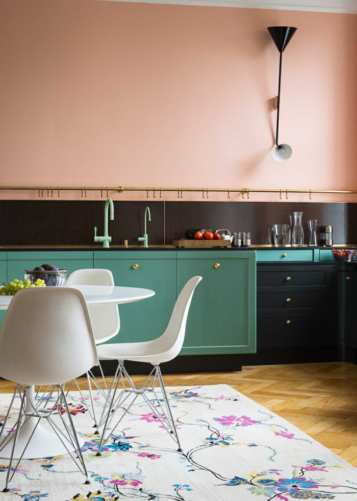 Kücheneinrichtung Idee, Wandfarbe Apricot, Schränke in Schwarz und Grün, weißer Teppich mit Blumenmuster