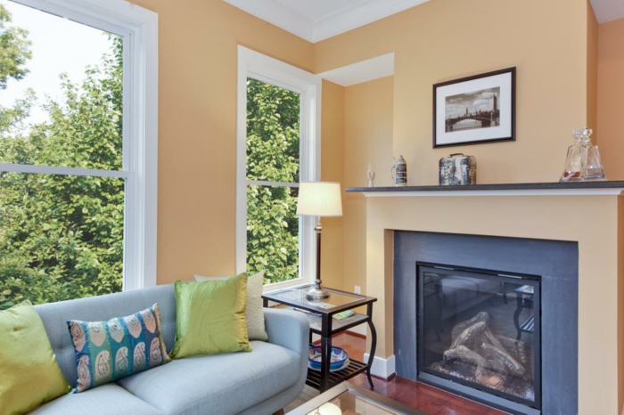 Wandfarbe Apricot, hellblaues Sofa mit bunten Dekokissen, Gemütlichkeit und Komfort in Wohnzimmer