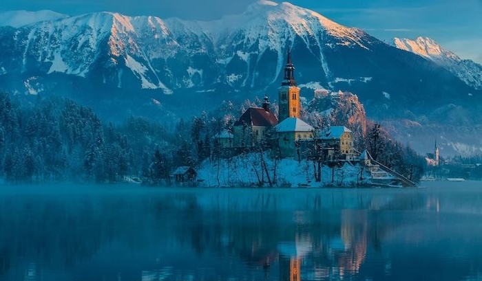 schöne winterbilder - see und eine insel mit einer kirche und kleinen häusern - winterberge mit schnee und ein wald mit bäumen und . schnee