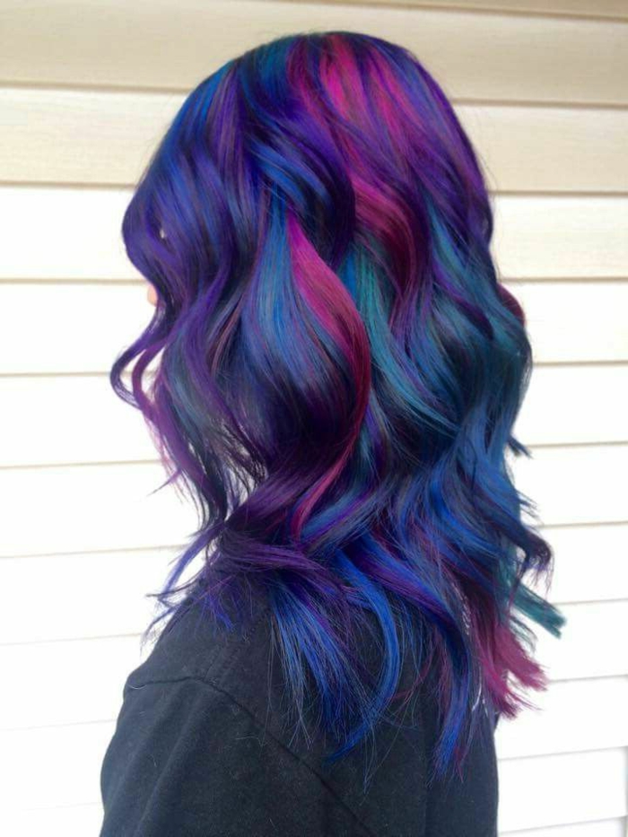leicht gewellte bunte Haare - dunkelblaues Haar mit violetten Strähnen, blaues Haar mit grünen Reflexen, mittellange dichte Haare, Wand mit Kunststoff-Paneelen