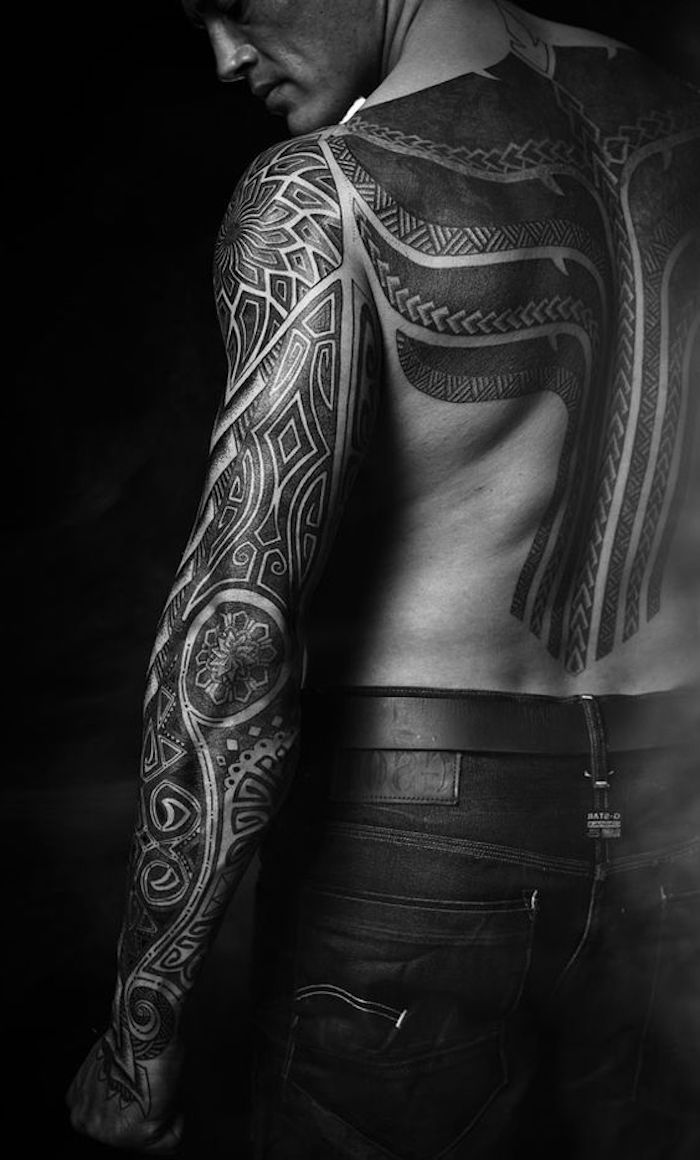 ein junger mann mit einer großen schwarzen maori tätowierung und mit schwarzen hosen - maorie tattoo bedeutung