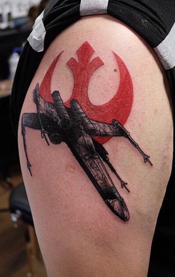 eine hand mit einem großen tattoo star wars mit einem fliegenden schwarzen star wars raumschiff und mit einem roten star wars logo 