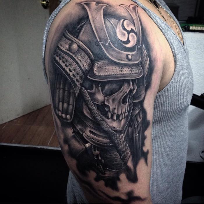 junger mann mit einer hand mit einer großen schwarzen tätowierung mit einer japanische rüstung und einem totenkopf - tattoo totenkopf