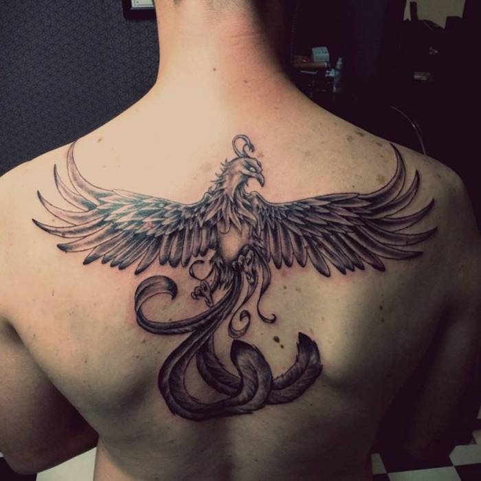 tattoo phönix rücken - ein mann mit einer schwarzen tätowierung mit einem fliegenden schwarzen phönix mit langen schwarzen federn 