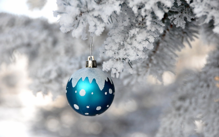 eine kleine blaue weihnachtskugel und ein baum mit schnee - ein romantisches winterbild