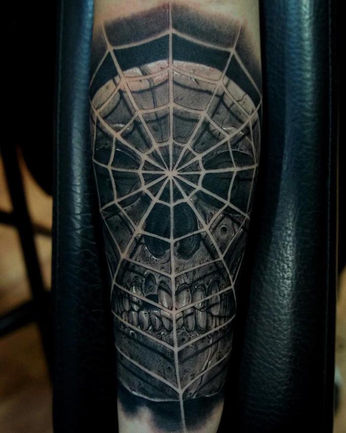 hand mit einem großen schwarzen tattoo totenkopf mit einem großen weißen spinnennetz