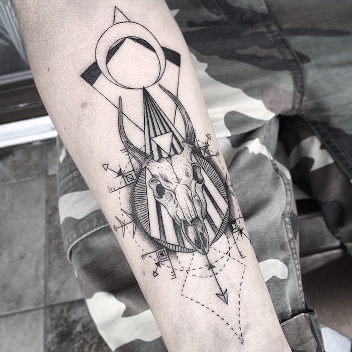 totenkopf tattoo bedeutung - eine hand mit einem tattoo mit einem weißen totenkopf eines tieres mit schwarzen hörnern 