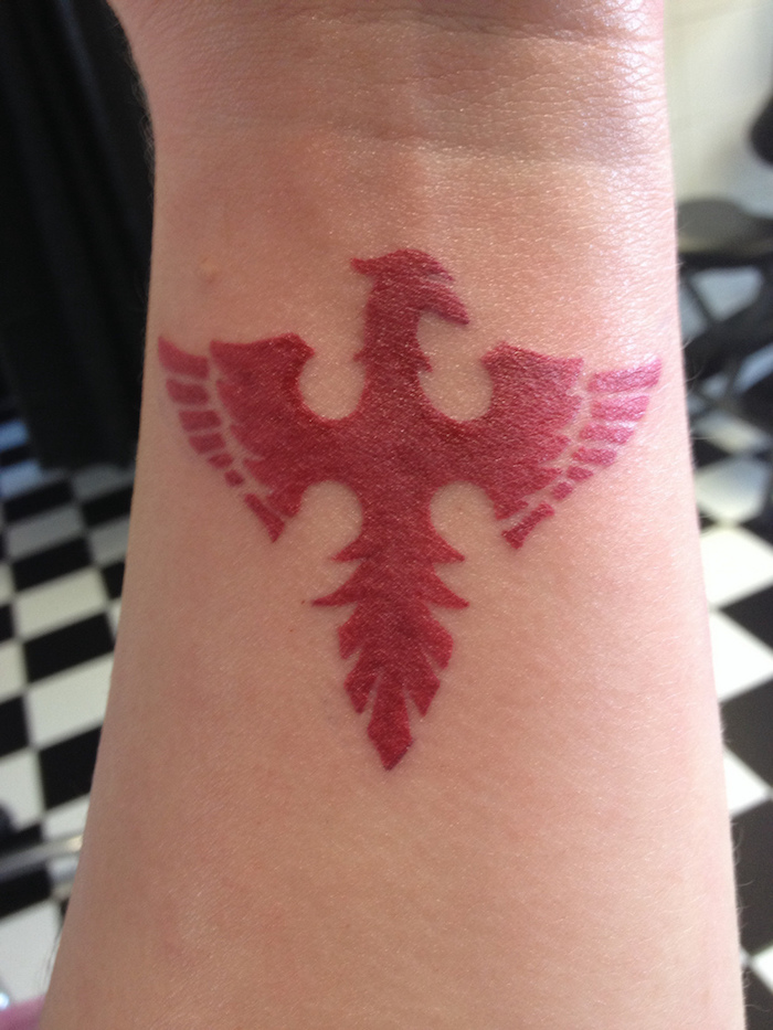 roter tattoo mit einem kleinen roten phönix mit roten flügeln - phönix tattoo am handgelenk
