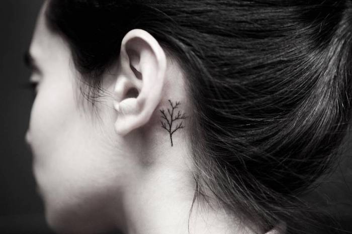 tattoo hinterm ohr motive - eine junge frau mit einem kleinen schwarzen tattoo hinter ihrem ohr mit einem kleinen schwarzen baum