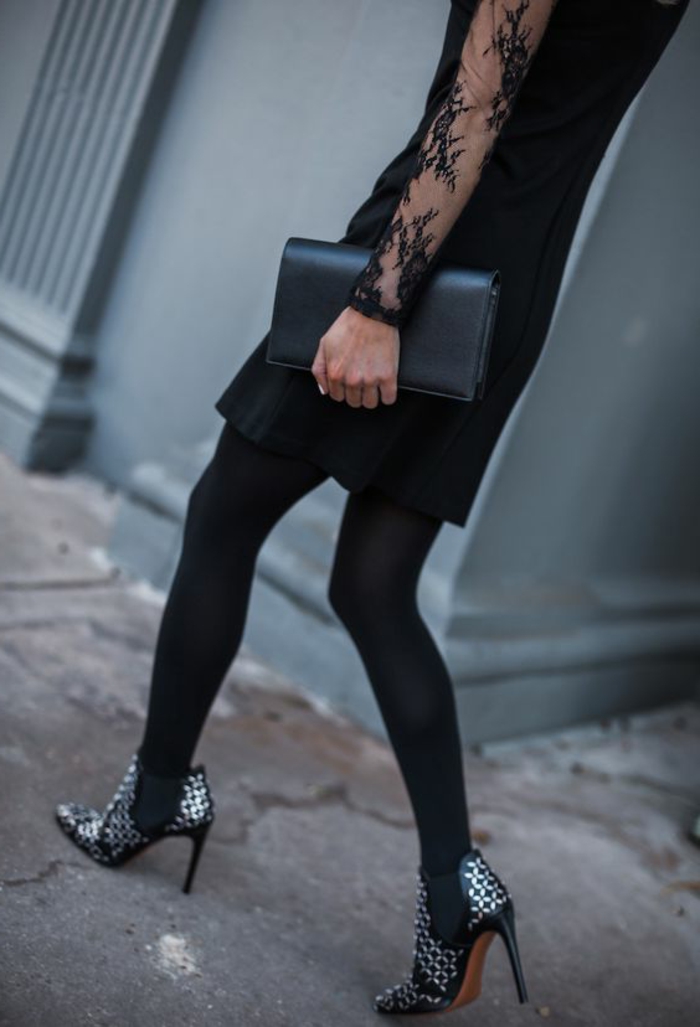 schwarzes Kleid mit mittlerer Länge mit feinem Design, Tüllärmel mit Applizierungen, schwarze Handtasche aus Leder, schwarze Winterstiefel mit Metallkapseln