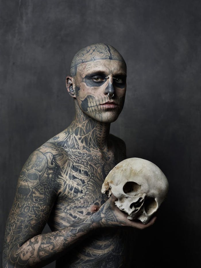 tattoo totenkopf - ein mann mit einem weißen großen totenkopf und mit vielen tätowierungen - ein tattoo mit einem großen weißen totenkopf mit schwarzen augen