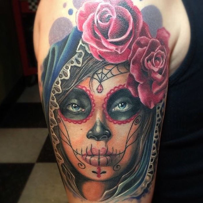 hand mit einem tattoo mit einer jungen verstorbenen frau mit roten lippen und einer schwarzen nase und einem schwarzen spinnennetz und zwei großen roten rosen