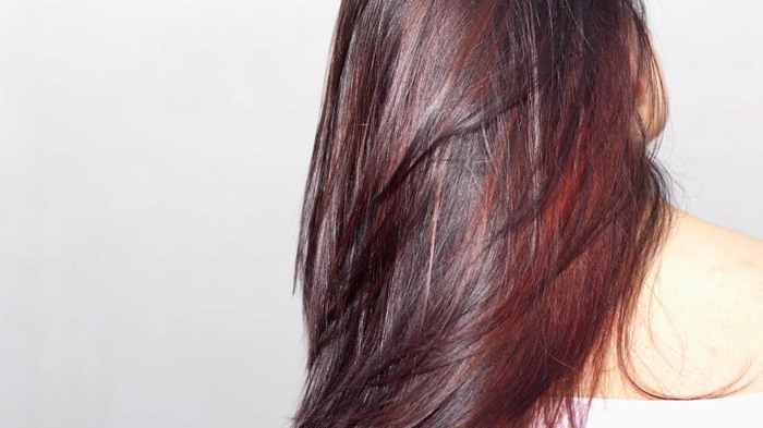 glänzende lebendige Haare mit dunklem Satz mit Mahagoni Farbschattierung und roten Reflekten auf den Längen, weiße Bluse-Schulterfrei, Bild mit leicht grauem Hintergrund