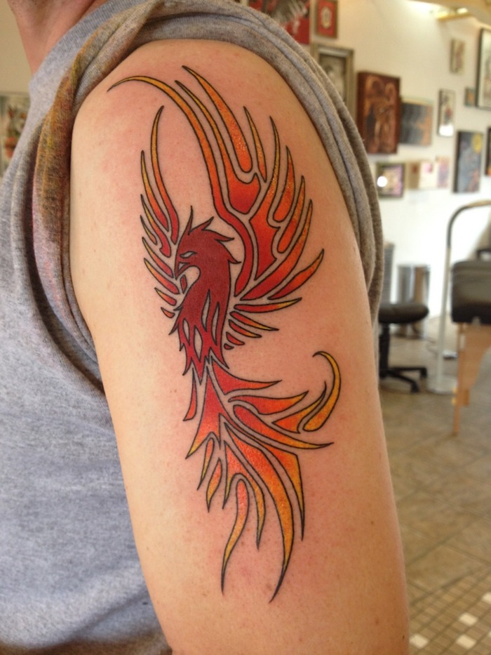 hand mit einem roten tattoo mit einem großen roten fliegenden phönix mit zwei flügeln mit roten, orangen und gelben langen federn, Tattoos Phönix aus der Asche